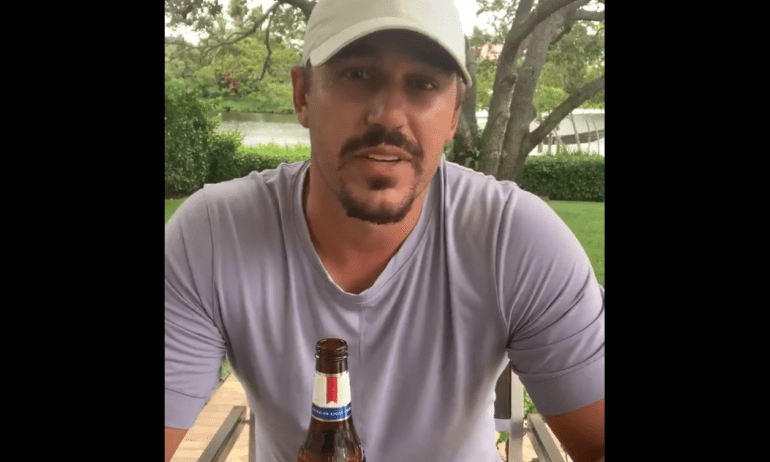 Brooks Koepka wearing a white hat and holding a bottle of beer