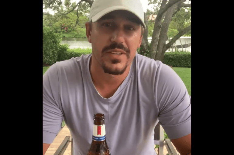 Brooks Koepka wearing a white hat and holding a bottle of beer