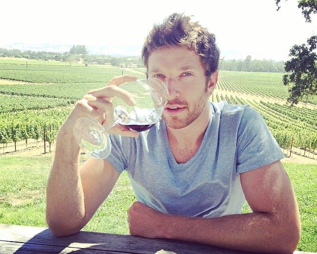 Brett Eldredge sitting on a table drinking from a glass