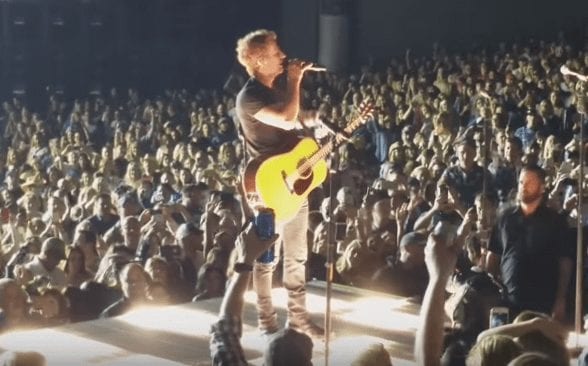 A man playing guitar in front of a crowd of people