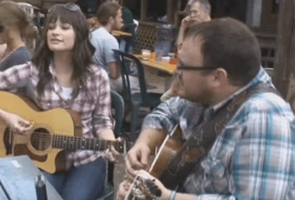 A man playing a guitar next to a woman playing a guitar