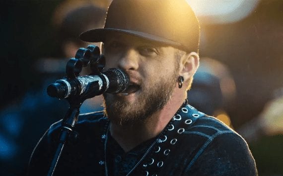 Brantley Gilbert with a beard and a hat with a microphone in front of him