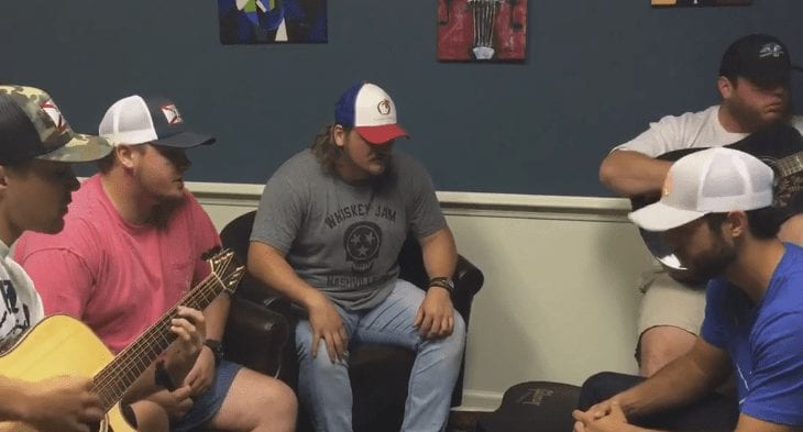A group of people sitting on a bench playing a guitar