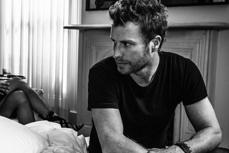 Dierks Bentley sitting on a bed