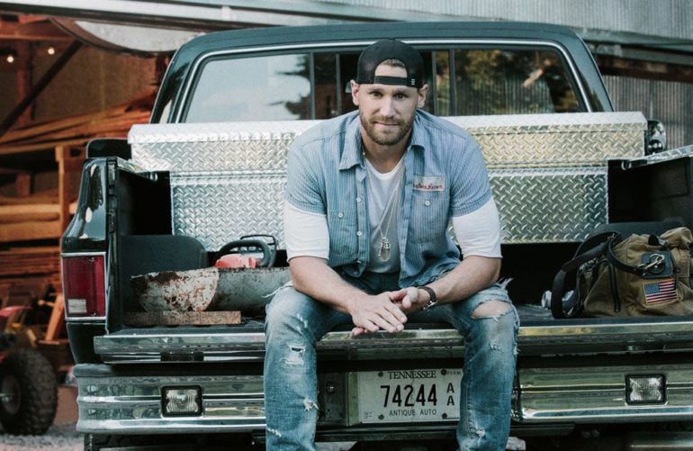 Chase Rice sitting in the back of a truck