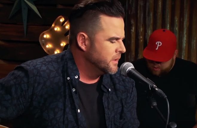 David Nail with a red hat and a microphone in front of a microphone
