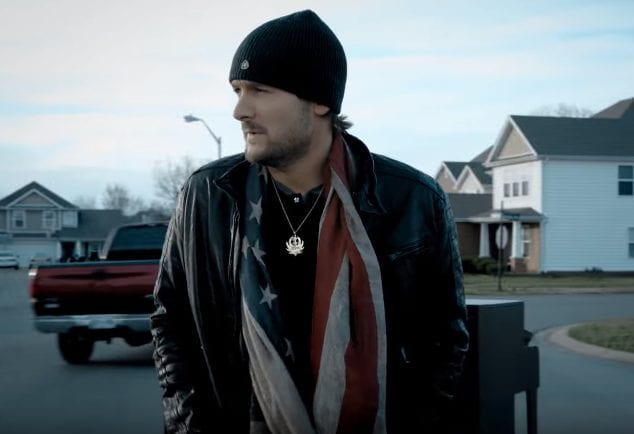 Eric Church wearing a black jacket and a red and white striped shirt