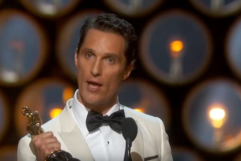 Matthew McConaughey wearing a suit and bow tie holding a trophy