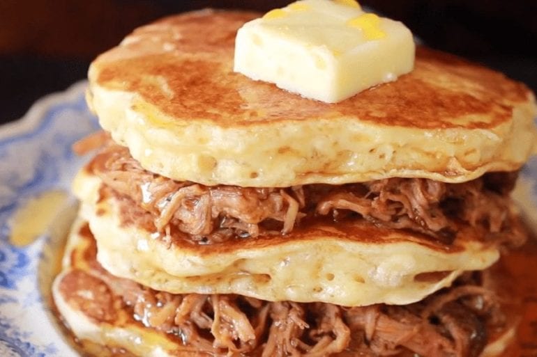 A stack of pancakes with bacon and cheese