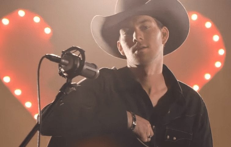 A man wearing a cowboy hat and singing into a microphone
