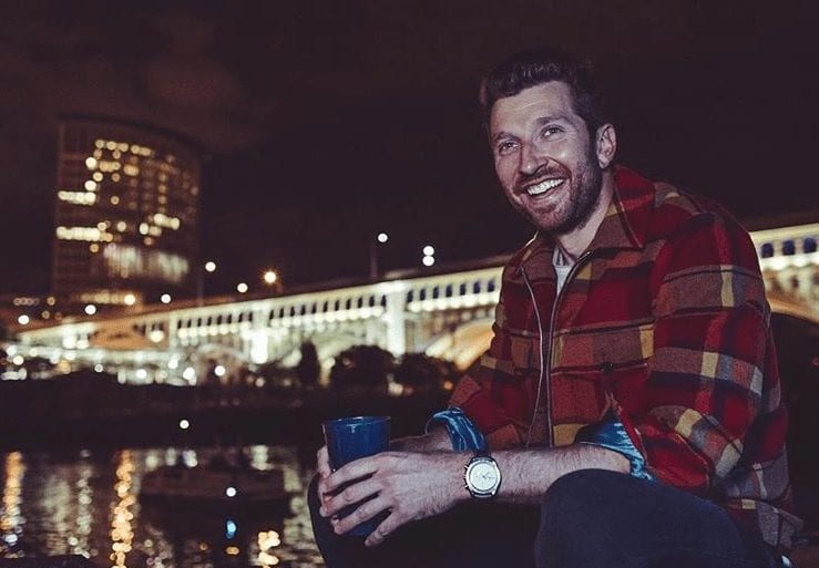 Brett Eldredge sitting on a ledge with a drink in his hand