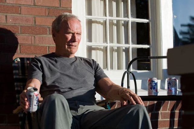 Clint Eastwood sitting in a chair holding a can