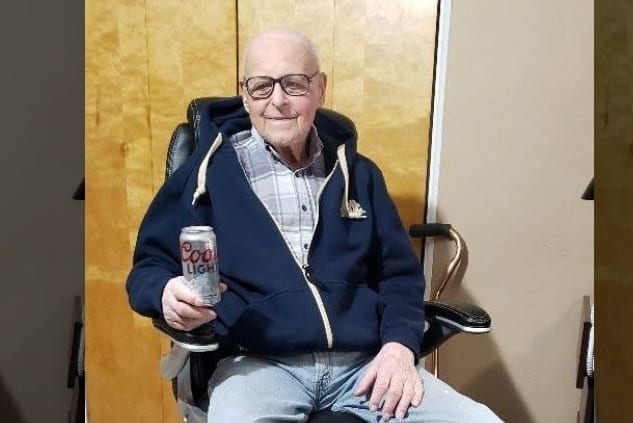 A man sitting in a chair with a can of soda