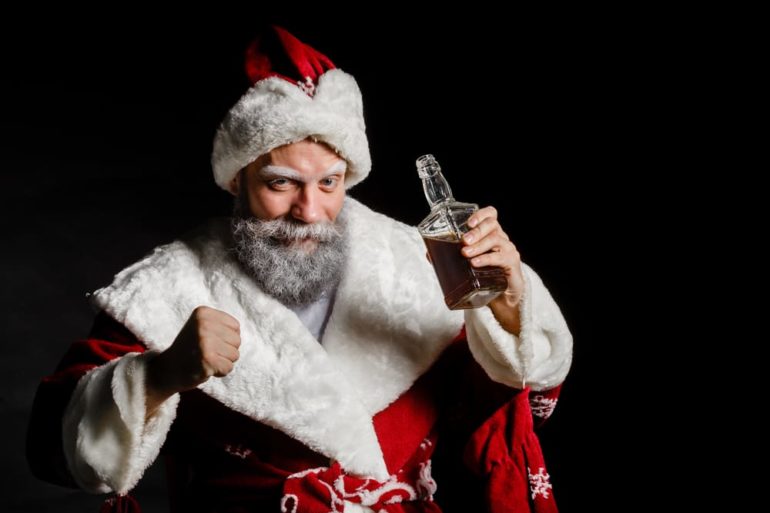 A person in a santa garment holding a glass of beer