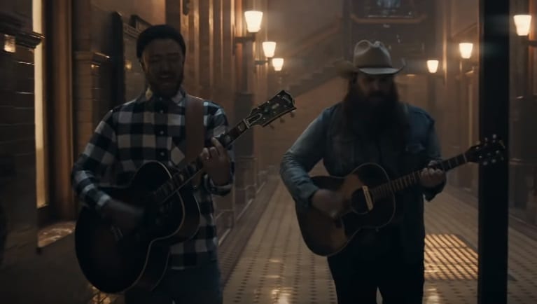 Two men in a hallway with guitars