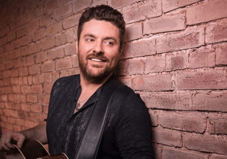 Chris Young smiling in front of a brick wall