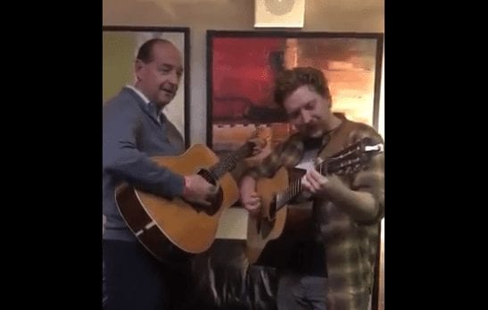 A man playing a guitar next to a man playing a guitar