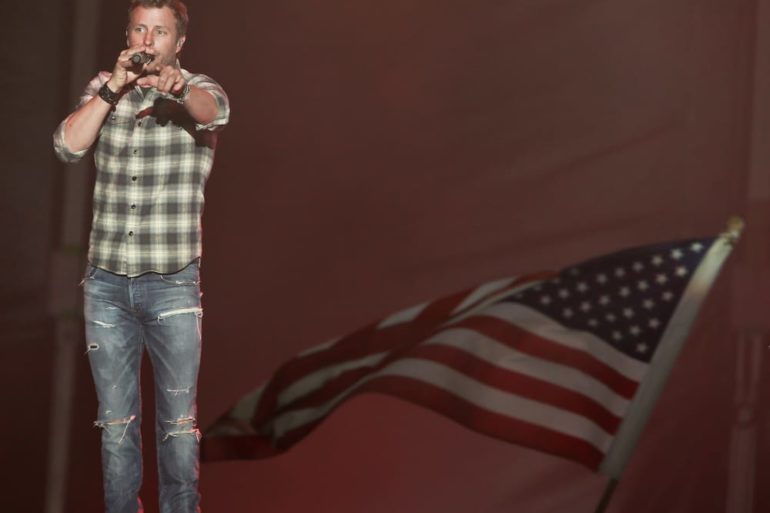 Dierks Bentley holding a microphone and a flag