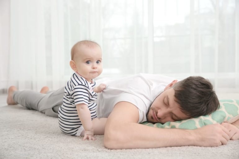 A person lying on the floor holding a baby