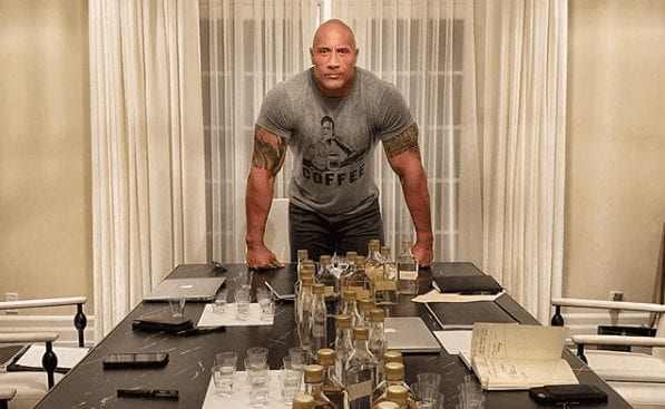 Dwayne Johnson standing next to a table full of glasses