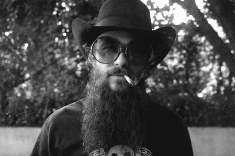 A man with a beard and glasses smoking a cigarette