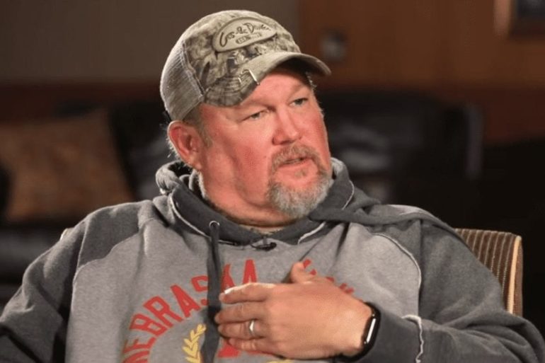 Larry the Cable Guy wearing a hat and holding a microphone