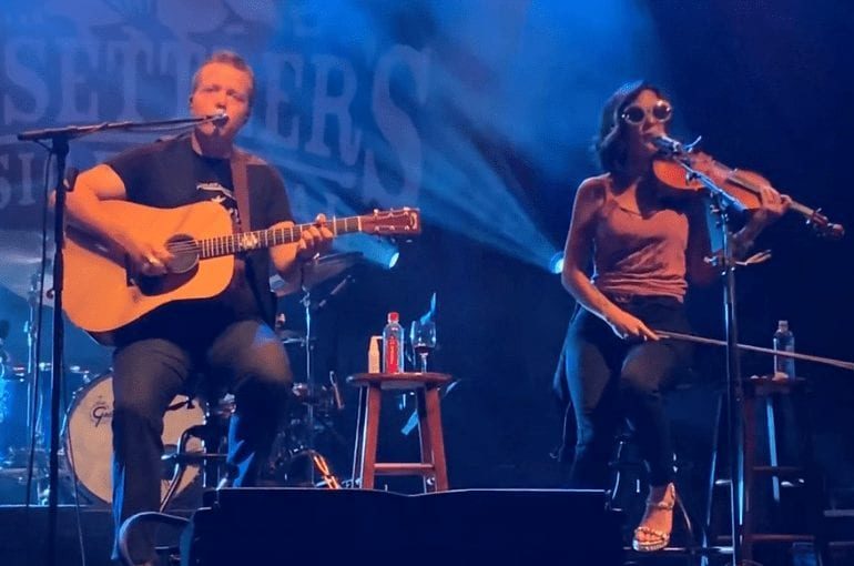 A man and a woman playing guitars on a stage