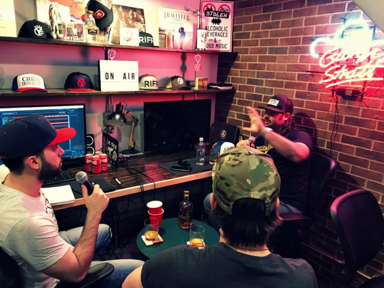 A group of men sitting at a table with drinks and video games