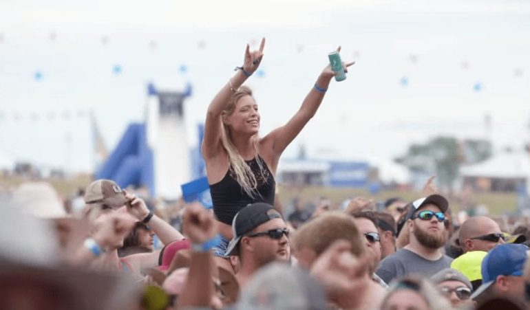 A person holding a bottle in the air with a crowd of people behind the