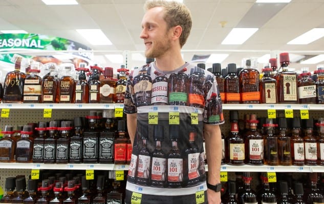 A man standing in front of a shelf of liquor bottles