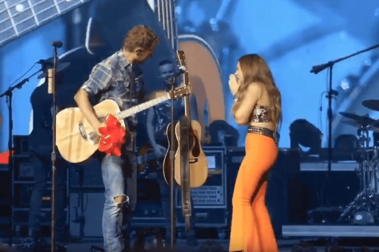 A man and woman playing guitars on a stage