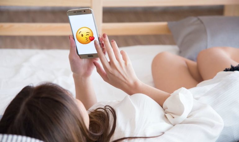 A woman lying on a bed holding a phone