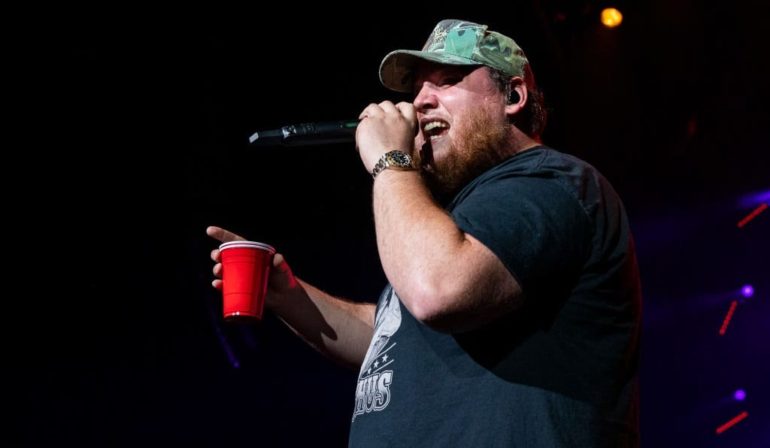 A man holding a red cup and singing into a microphone