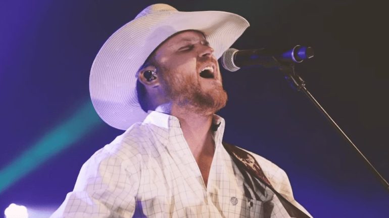 A man wearing a white hat singing into a microphone