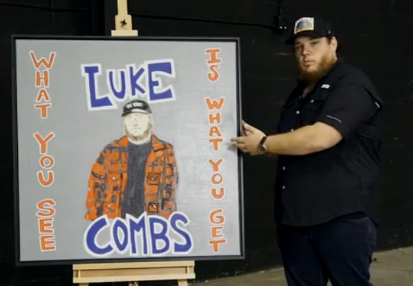 Luke Combs pointing at a poster