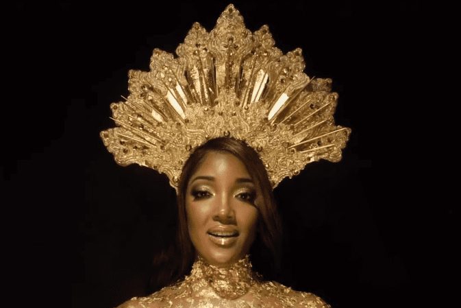 Mickey Guyton with a large gold crown