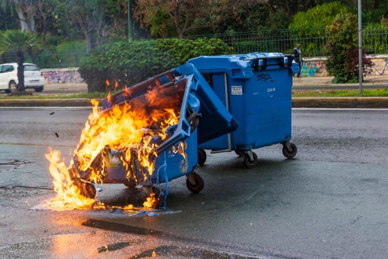 A blue garbage dumpster with flames
