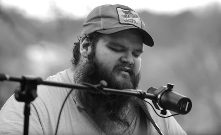 John Moreland wearing a hat and holding a microphone