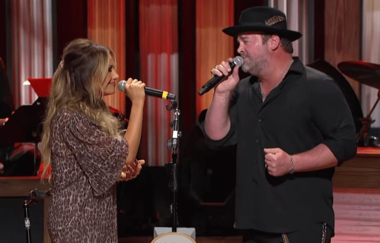 A man singing into a microphone with a woman singing into a microphone