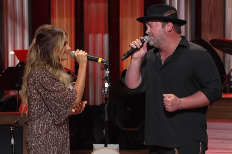 A man singing into a microphone with a woman singing into a microphone