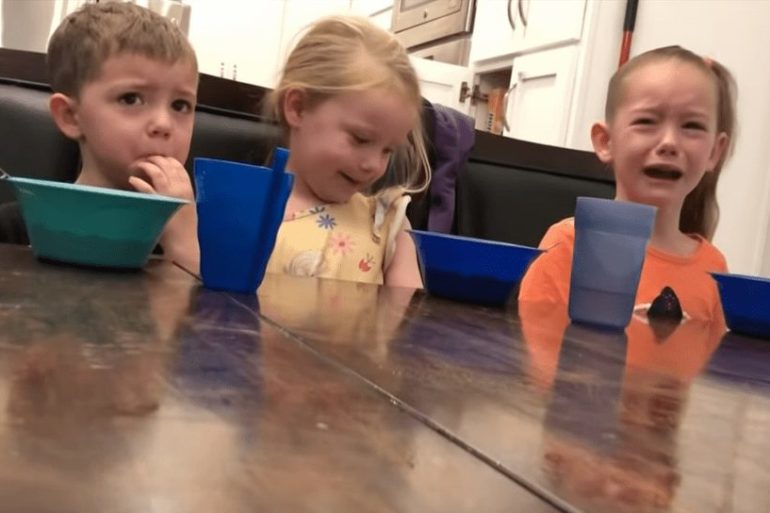 A group of children sitting at a table with blue cups