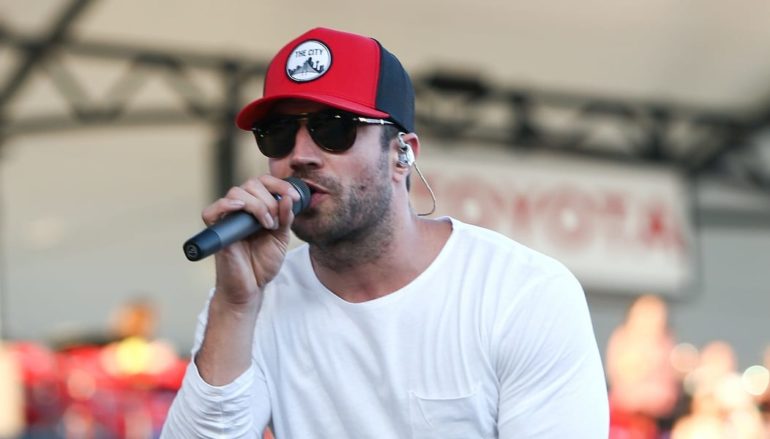 A man wearing a red hat and sunglasses singing into a microphone
