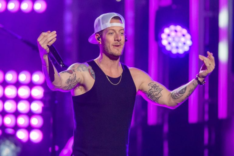Tyler Hubbard with tattoos and tattoos holding a microphone