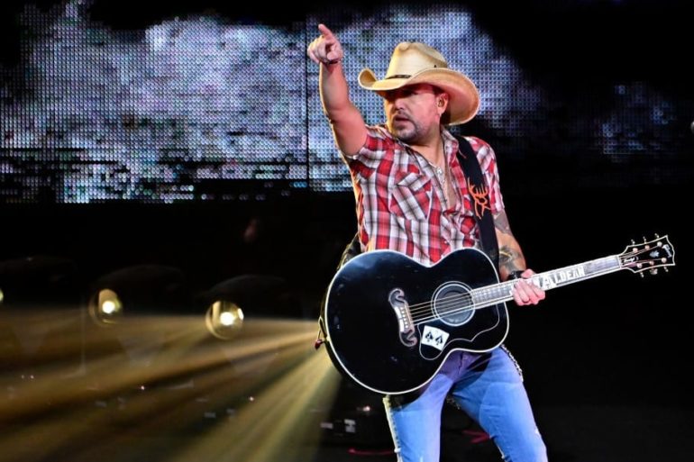 Jason Aldean playing a guitar on a stage