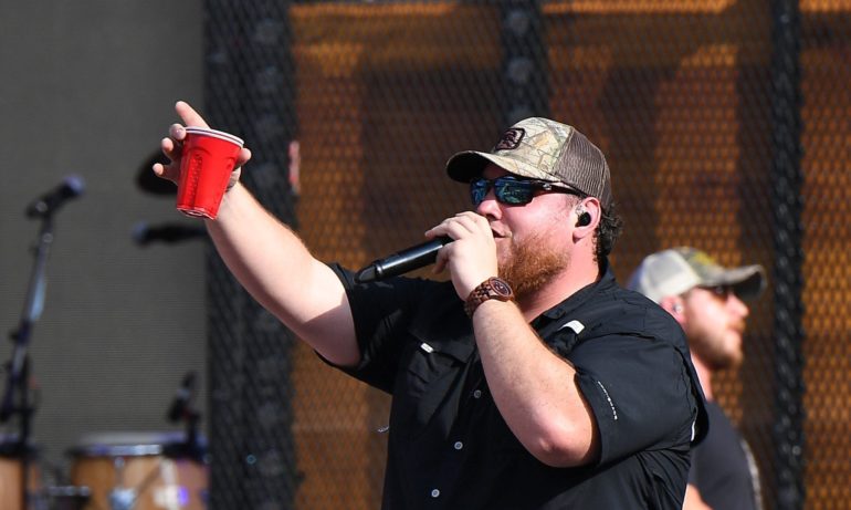 A person holding a red cup and singing into a microphone