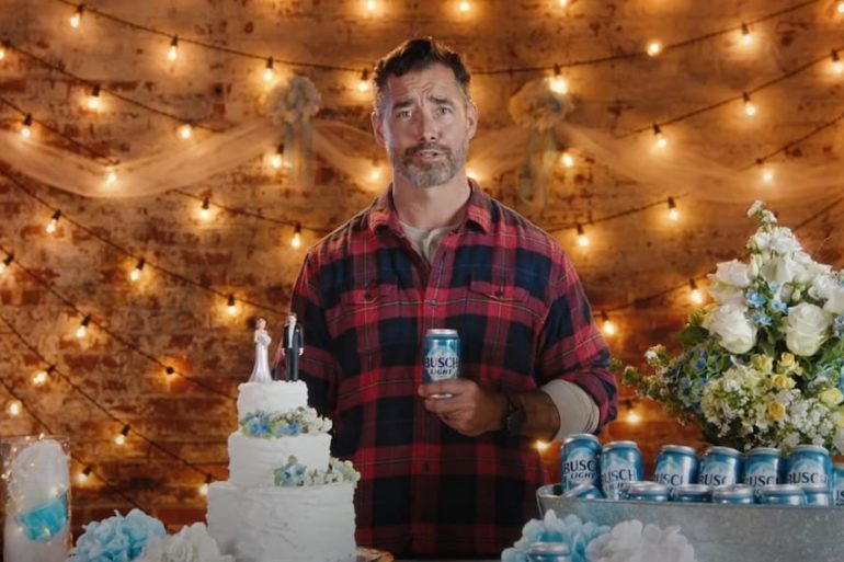 A person holding a can and standing next to a cake