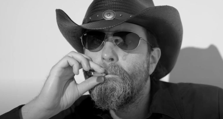 A man wearing a hat and smoking a cigarette