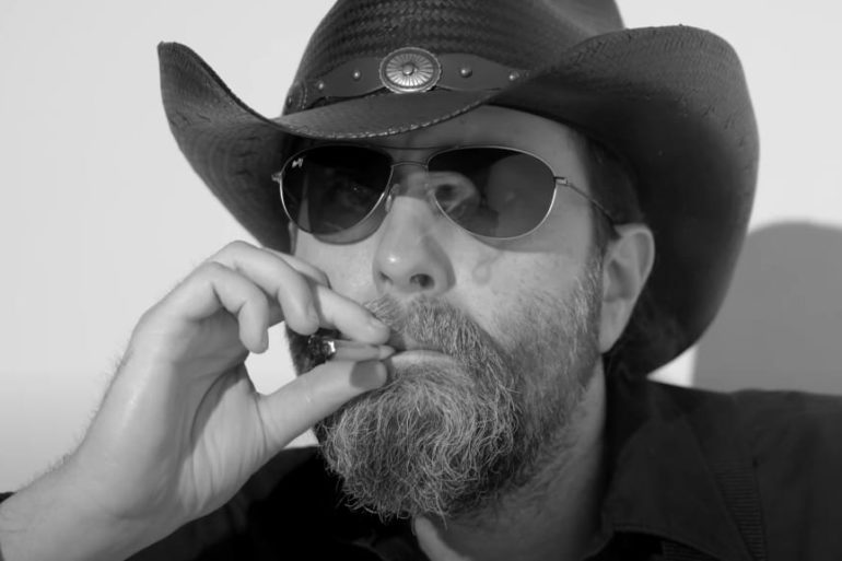 A man wearing a hat and smoking a cigarette