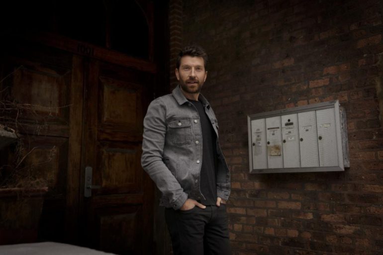 Brett Eldredge standing in front of a wall with white boxes on it