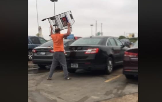 A person holding a large box in a parking lot